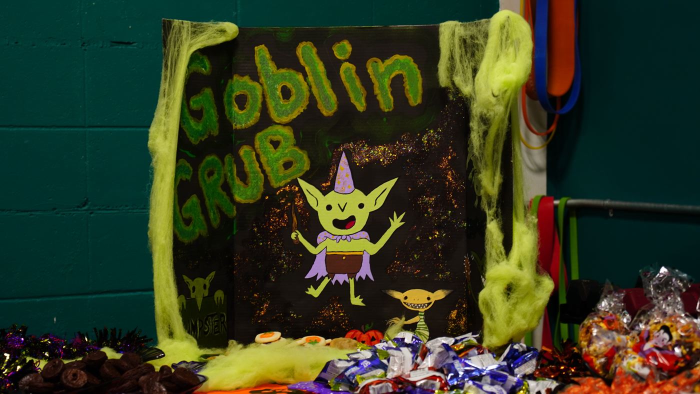 A table of Halloween treats under a hand-painted Goblin Grub sign