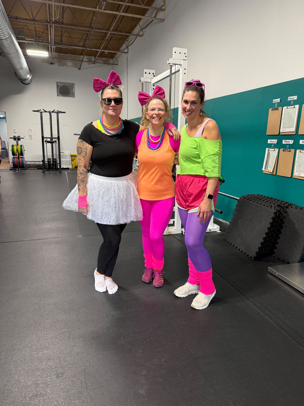 Three Adventurers in neon 80s workout costumes on the gym floor