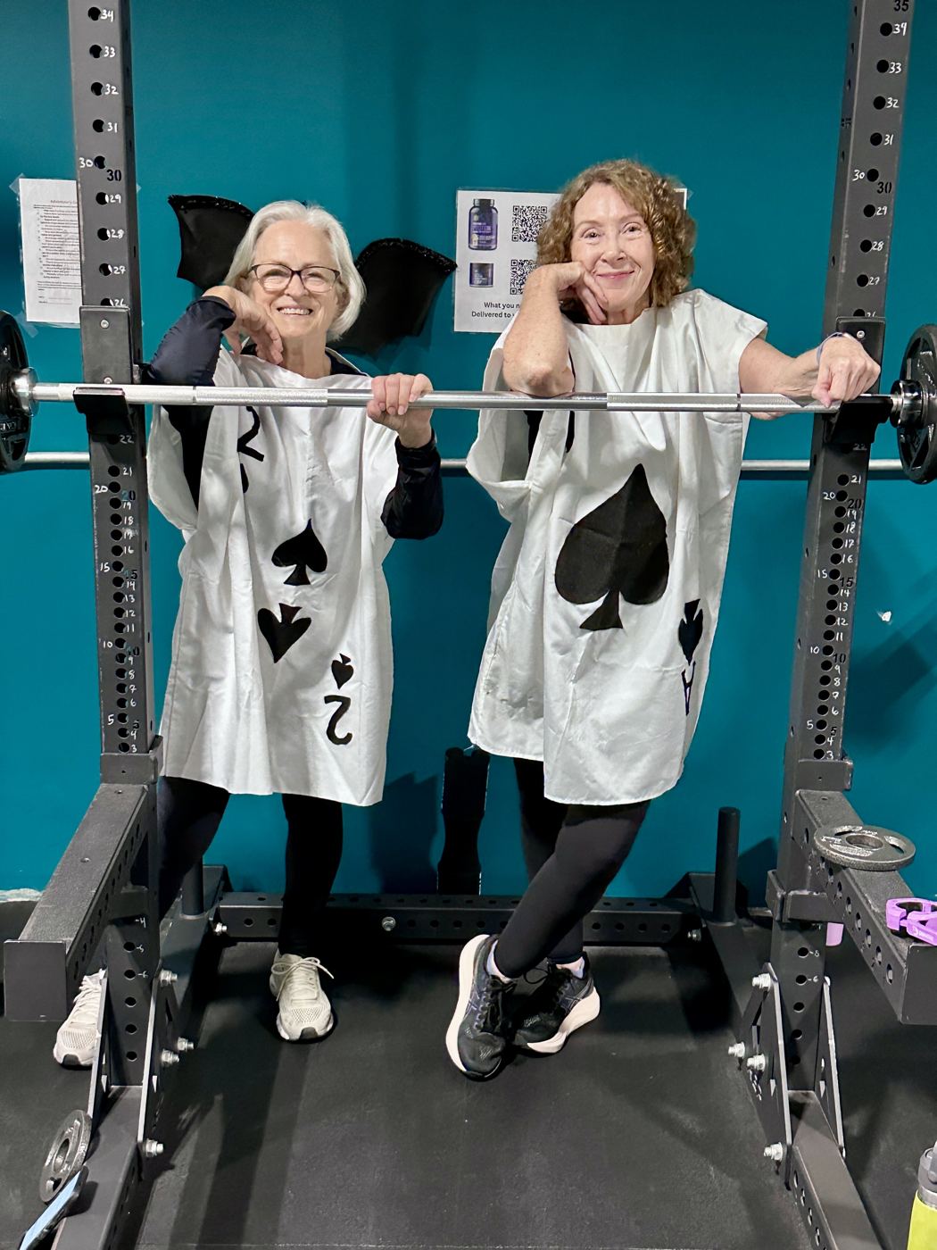 Two Adventurers dressed as playing cards leaning on a barbell